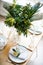 Beautiful springtime table setting with green leaves and mimosa branches, bright white table dinner decoration