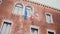 Beautiful steadicam low angle shot of old official building with three waving flags EU, Italy and Venice on the facade.