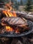 A beautiful steak being cooked to perfection over an open flame in the great outdoors. The flames lick up the sides of the grill