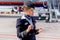 Beautiful stewardess dressed in official dark blue uniform of Aeroflot Airlines on airfield. Passenger jet aircraft on background.