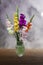 Beautiful still life with multicolored gladioli in a glass vase marble gray and wooden background