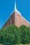 Beautiful stone church with white spire - clear vivid blue skies with lush green bushes in front - wide angle - green, brown, whit