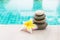 Beautiful stone stack with fresh Plumeria flower on swimming pool edge with space on blurred blue background