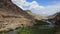 Beautiful stormy mountain river of bluish hue flows rapidly among large stones and boulders close up. Mountain river