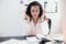Beautiful stressed young office worker sitting at desk holding head because of pain in office. Woman with dark hair