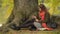 Beautiful student girl using tablet outdoor sitting on tree near lake