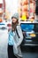 Beautiful student woman ready get in into her car parked on city street. Cute smiling woman wearing autumn casual street style