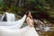 Beautiful stylish bride posing near the waterfall outside