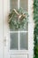 Beautiful stylish Christmas wreath with a satin bow on the white door of the house