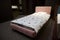 Beautiful stylish single bed for a baby girl upholstered in pink velour fabric displayed for sale in a furniture store. Home