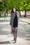 Beautiful stylish woman in black dress and cozy trench coat walk in city park. Spring outdoor lifestyle. Happy woman walking.