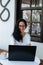 Beautiful stylish woman in glasses sitting in a street cafe and working on a laptop.