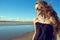 Beautiful stylish woman with the wind in her hair wearing black open shoulder top and trendy round mirrored sunglasses at the pool