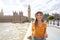 Beautiful stylish young woman looking to the side walking on Westminster Bridge in London on sunny day, England, UK