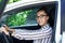 Beautiful successful smiling rich business woman in white suit sitting in gray car salon , wearing glasses talking on