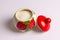 A beautiful sugar bowl with painted strawberries and a red lid, filled with white sugar on a white background