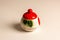 A beautiful sugar bowl with painted strawberries and a red lid, filled with white sugar on a white background