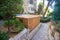 A beautiful sukkah made of wood inside the courtyard of a building, surrounded by trees and plants,