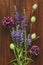 A beautiful summer bouquet, wildflowers, wild onions, Veronica long-leaved violet on a wooden background of black walnut.