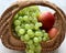 Beautiful summer fruits in a basket. Yellow red apples and white grapes.