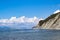 Beautiful summer landscape, bright blue sky with clouds, steep cliffs with trees, stone wild beach