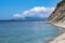 Beautiful summer landscape, bright blue sky with clouds, steep cliffs with trees, stone wild beach