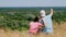 Beautiful summer landscape. man and little girl, dad and daughter, sit on cliff edge, admiring amazing panorama of green