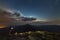 Beautiful summer night in mountains. Profile silhouette of young tourist hiker man with flashlight standing alone on rocky mountai