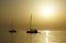 Beautiful summer sunset background in beige color tone with silhouette of two yachts on the sea horizon line