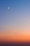 Beautiful summer sunset - dark blue sky with visible moon and orange horizon