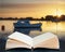 Beautiful Summer sunset landscape over low tide harbor with moored boats coming out of pages of inaginary book