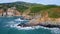 Beautiful sunny coastal landscape drone view. Ocean splashing rocky shoreline