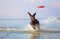 On the beautiful sunny day at the lake the playful dog is jumping from the water. Splashes and waves. Silhouette reflection.