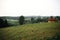 Beautiful sunny meadow with wooden cabins on hills among woods at sunset in mountains. View on evening hills in Carpathian