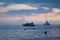 Beautiful sunrise on calm sea with smooth waves, colorful light sky with fluffy clouds, yacht and boat on horizon. Marine.