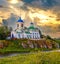 A beautiful sunrise church on the riverbank on a cliff with a beautiful dawn sky in the background. Russia, the Urals.