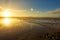 Beautiful sunset on the beach with water reflections, seagulls on the sand and windmills on background