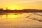 Beautiful sunset on the beach with water reflections, seagulls on the sand and windmills on background