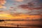 Beautiful sunset on the coast with light with a luminous cloud. Silhouettes of people walking on the beach.