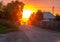 Beautiful sunset on the dusty street in front of the sun. Pink and orange sunset in the countryside