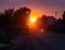 Beautiful sunset on the dusty street in front of the sun. Pink and orange sunset in the countryside