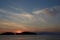 Beautiful sunset on lake and islands. The sun hid behind the islands covered with forest. Cirrus, white clouds over the lake