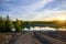 Beautiful sunset on the lake in springtime. Eroded ground in the foreground, birches and pine trees in the background. Setting sun