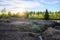 Beautiful sunset on the lake in springtime. Eroded ground in the foreground, birches and pine trees in the background. Setting sun