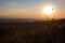 Beautiful sunset landscape shot from a hill: colored sky with traces of flying planes, sunset sun, lakes in the distance, dry gras