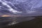 Beautiful sunset over the Atlantic Ocean at Costa da Caparica beach in Lisbon, Portugal. Dramatic sky and clouds in the background