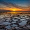 Beautiful sunset over the ocean with rocky beach and tidal pools in the foreground