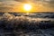 Beautiful sunset over the ocean with a yellow horizon and tidal waves crashing the shore