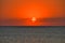 Beautiful sunset over the surface of the sea in red, a horizon line, a small cloud cover