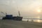 Beautiful Sunset scene on beach with shipwreck and silhouette of bicycle